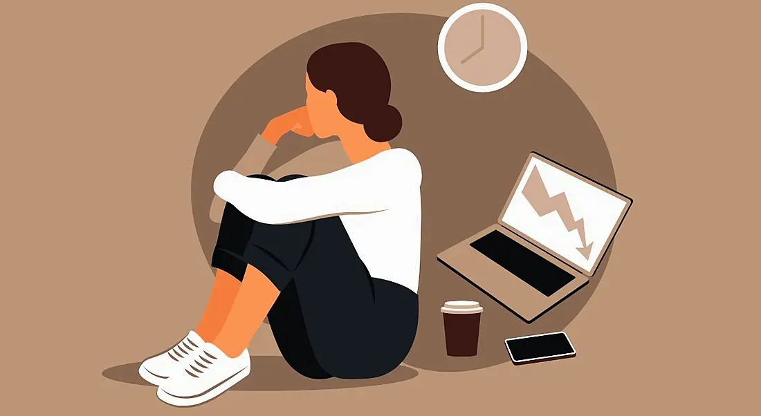 A cartoon showing a Gen Z worker suffering from burnout. She is facing away from her laptop, coffee and phone. The background is brown.