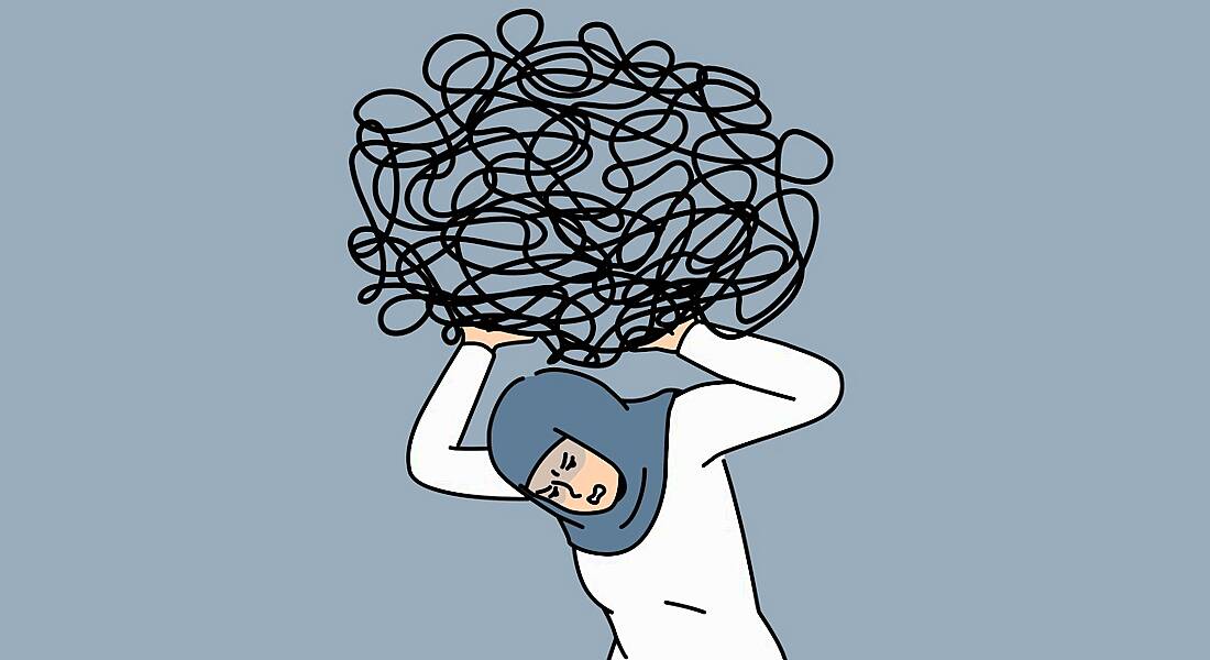 Cartoon of a stressed out worker crouching under the weight of a heavy workload, signified by a large black scribble over her head.