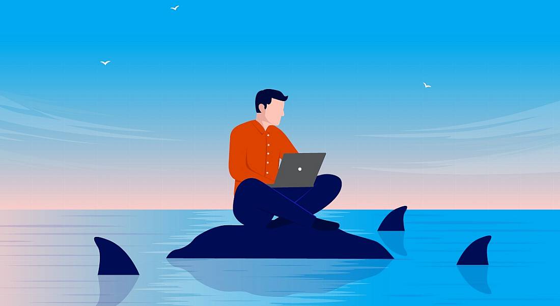 Cartoon of a worker as an insider threat sitting on a rock using a laptop as sharks representing cybercriminals circle around him.