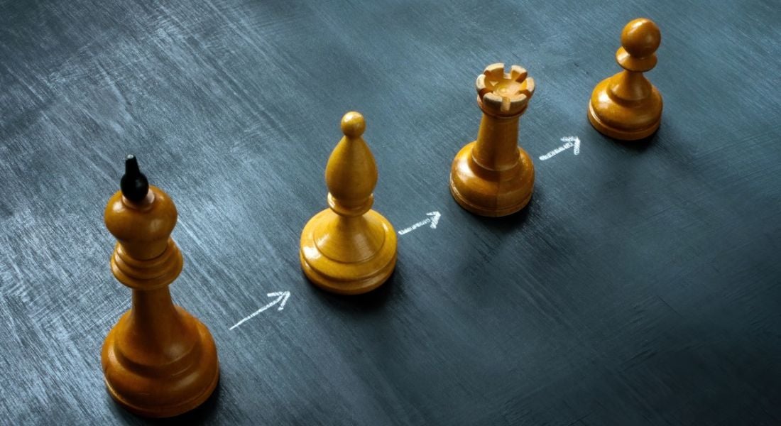Four chess pieces in a row with arrows in between them to illustrate a succession planning concept.