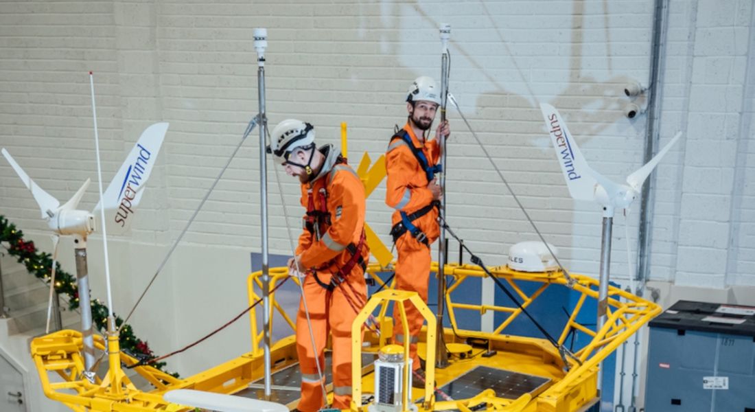 Two men in high visibility gear standing on top of a yellow buoy in a large room. They are technicians with the company Green Rebel.