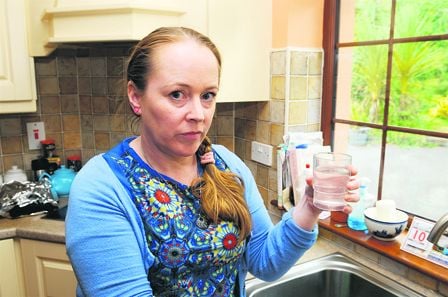 Mary Egan with a glass of cloudy water and, right, her bath, filled recently with tap water.