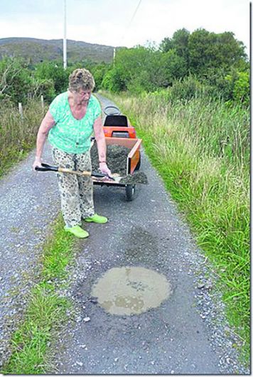 Pensioners forced to fill potholes on access road Image