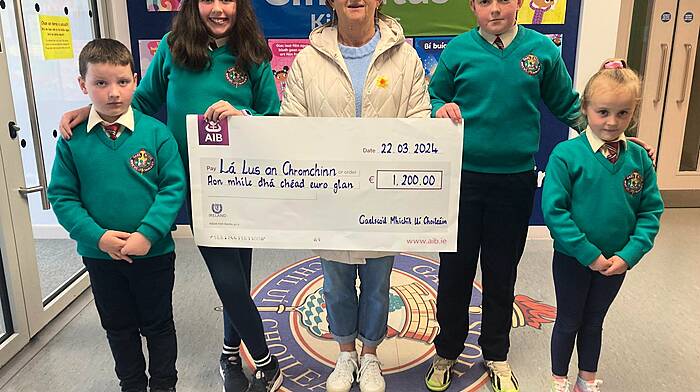 Pupils at the Gaelscoil had a no uniform day and instead dressed up in yellow and green (the colours of the daffodil flower) on Daffodil Day and made cash contributions. Many of their families also donated online and as a result, the school raised a total of €1,200. Therese Hayes (centre), one of the main organisers of Clonakilty Daffodil Day for the last 25 years, accepted the cheque recently from student representatives. From left:  Sam Ó Cinnseabháin (Naí Bheaga), Chloe de Faoite agus Rory Ó Coileáin (both Rang 6) agus Kylie Ní Néill (Naí Bheaga).