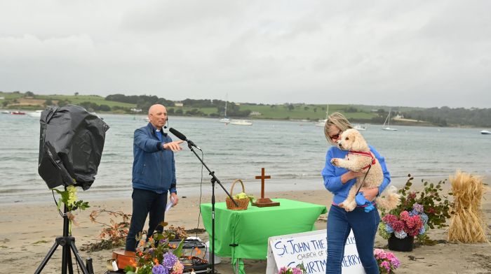 Rev Kingsley Sutton praying at the Pet Church Service and Harvest Thanksgiving on the beach in Courtmacsherry as Dorothy Draper, Clonakilty and her dog “Bailey” walk past.  (Photo: Martin Walsh)