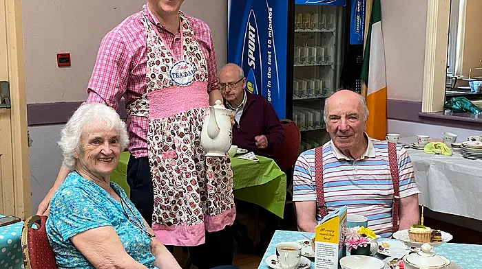 Michael and Frances O’Halloran, and with Jim Cooney behind Aindrias Moynihan, all enjoying a cup of tea at the annual tea day in Macroom which was held in aid of the Alzheimer’s Society of Ireland.
