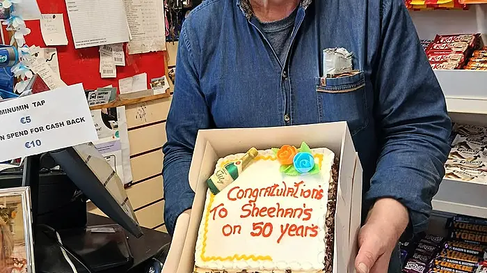 Dermot Sheehan behind the counter of his shop with a celebratory cake to mark the past 50 years of business in Goleen.