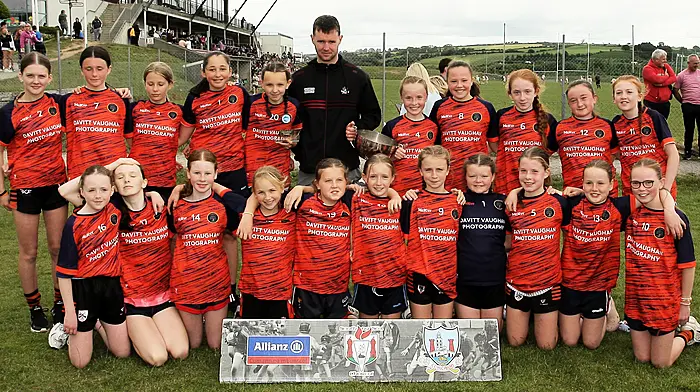 Roinn 2 Girls winners Kealkill NS receive the trophy from Cork footballer Maurice Shanley. (Photo: Paddy Feen)