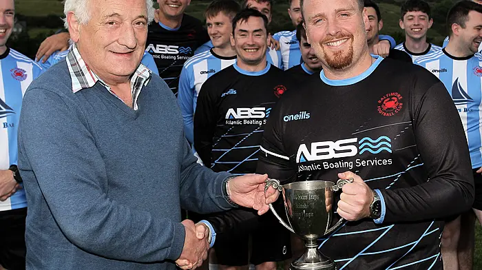 Ronnie Tanner treasurer of the West Cork League presents the trophy to Kieran Lynch captain of the Baltimore FC team that won the O'Brien Water Srvices.com Championship.