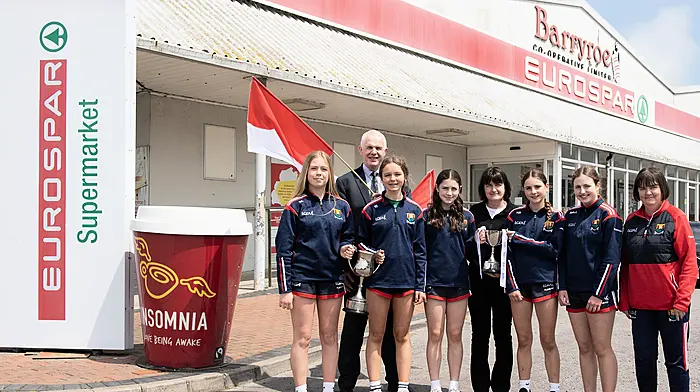 The Ibane members of the Cork team that won the All-Ireland U14 platinum final and their coach Mary Harrington on a visit to the EuroSpar Supermarket Barryroe Co-Op with the Munster and All-Ireland trophies; Kate Collins, John Cuddihy (Eurospar Barryroe), Niamh Doyle, Aoife Harte, Christine Cahalane (Eurospar Barryroe), Aoife Walsh, Aibhlin McCarthy and Mary Harrington. (Photo: Martin Walsh)