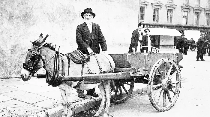Man with donkey and cart at standing at the top of Market Street, Skibbereen, with the Square in the background, c1920s.