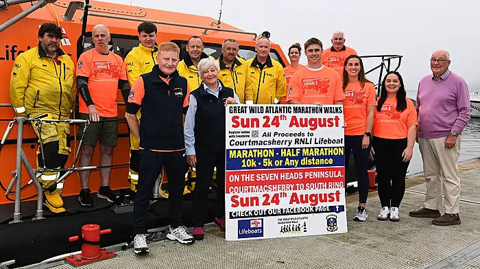 Munster and Ireland rugby star Jack Crowley, who is a familiar visitor to the Courtmacsherry area, launched the 2025 Great Wild Atlantic Marathon Walks in aid of the Courtmacshery RNLI at the weekend.  The organisers wore special electric orange tee shirts which are available at the Courtmacsherry Community Shop.  From left: Ken Cashman, Richard O'Flynn, Taylor Murphy, Vincent O'Donovan, Simon Locke, Angela Veldman, Tadgh McCarthy and Denis Murphy, Aoife Daly, Jack Crowley, Micheál Hurley, Emma O'Donovan, Elaine Kirby and octogenarian Tom McGrath, a granduncle of Jack Crowley, both of whom holiday in Dunworley. The  event that will take place on Sunday August 24th, is the ninth iteration, and has so far raised a sum of €73,012.                                      (Photo: Martin Walsh)