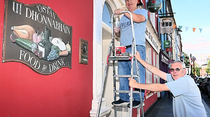 Painter Patrick O'Keefe from Clonakilty doing some decorating on the facade of O'Donovan's Hotel with staff member Hayden O'Donovan holding the ladder.   (Photo: Martin Walsh)