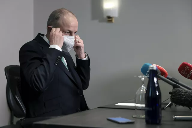 Taoiseach Micheal Martin taking off a mask at a press conference