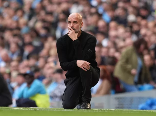 Pep Guardiola kneels on the touchline