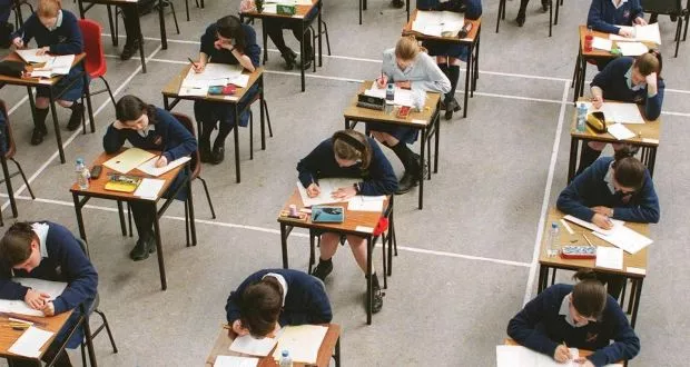 children in school sitting at their desks, writing